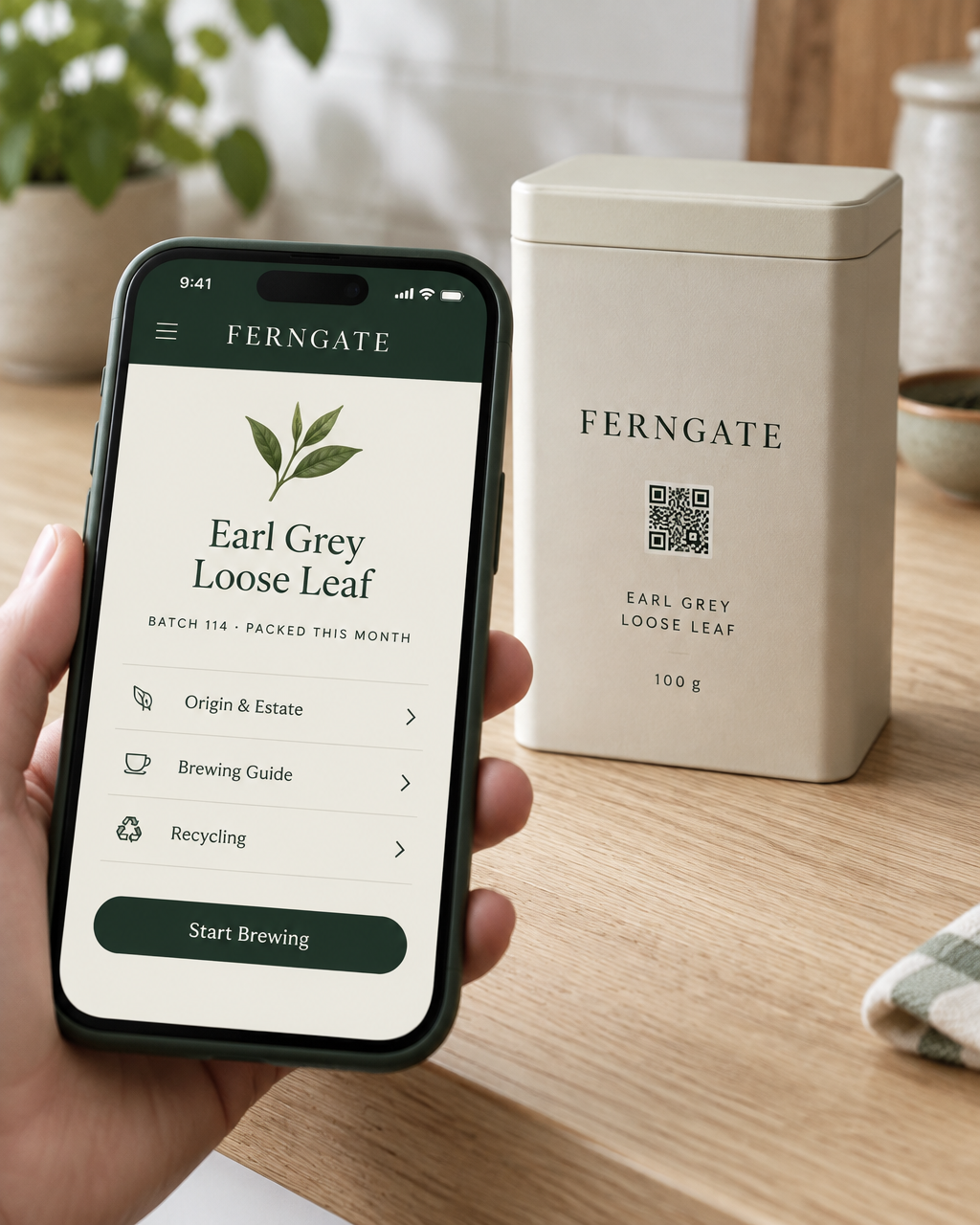 A hand scanning the code printed on a FERNGATE tea caddy, with the brand's own page on the phone
